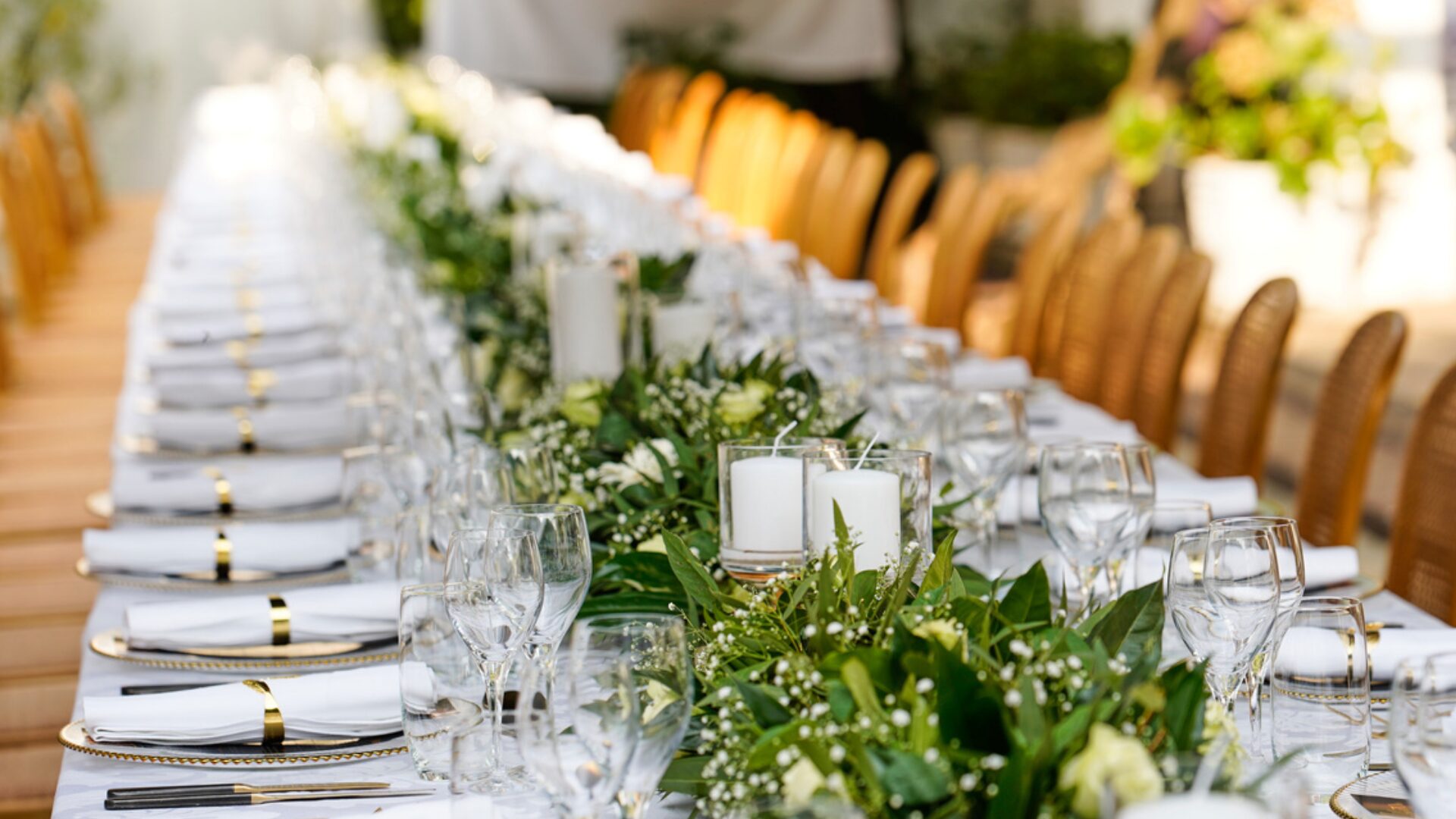 Long banquet table styled with candles and greenery