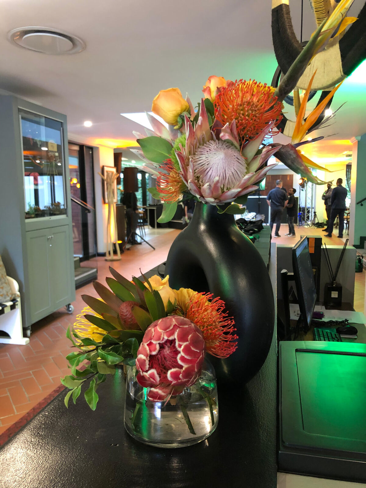 King protea and pincushion arrangements on a reception desk